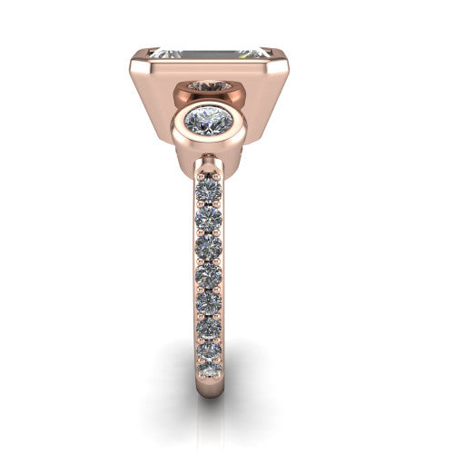 Chloe emerald three stone engagement ring in 18K Rose Gold, side profile showing the round bezel side stone and the pavé diamonds running down the shank