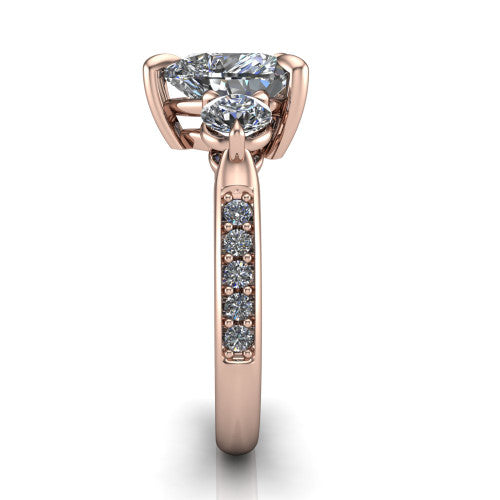 Blake heart three stone engagement ring in 18K Rose Gold, side profile showing the round side stone and the pavé diamonds running down the shank