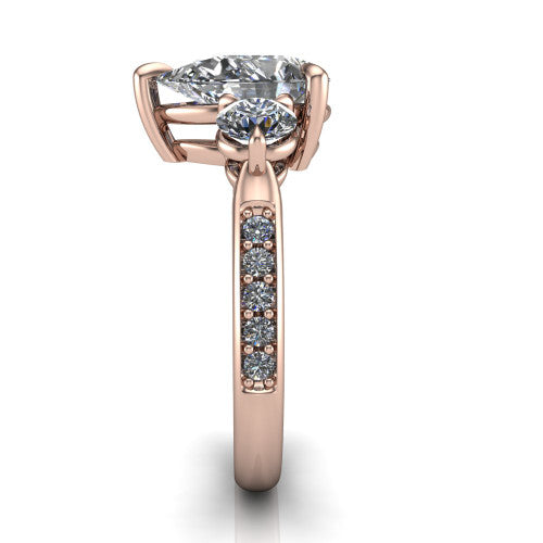 Blake pear three stone engagement ring in 18K Rose Gold, side profile showing the round side stone and the pavé diamonds running down the shank