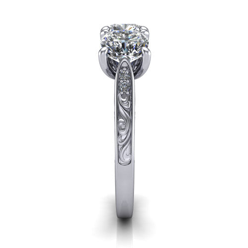 Navy cushion three stone engagement ring in Platinum, side profile showing the vintage engraved filigree band and the raised three-stone setting