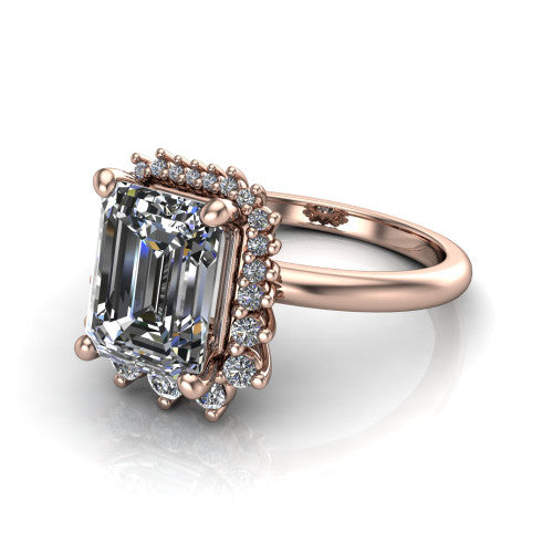Matilda emerald halo engagement ring in 18K Rose Gold, three-quarter perspective showing the step-cut emerald center diamond inside a sunburst halo of pointed rays with round accent diamonds clustered between them