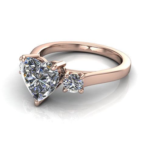 Olivia heart three stone engagement ring in 18K Rose Gold, three-quarter perspective showing the brilliant heart-shaped center diamond flanked by two round side diamonds on a squared flat-top shank
