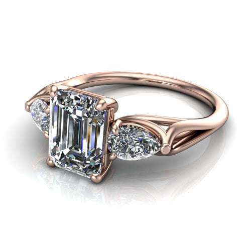 Journee emerald three stone engagement ring in 18K Rose Gold, three-quarter perspective showing the step-cut emerald center diamond flanked by two pear side diamonds set sideways on tapered cathedral shoulders