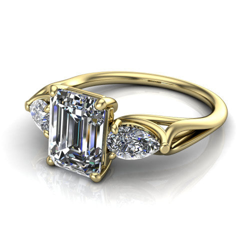 Journee emerald three stone engagement ring in 18K Yellow Gold, three-quarter perspective showing the step-cut emerald center diamond flanked by two pear side diamonds set sideways on tapered cathedral shoulders