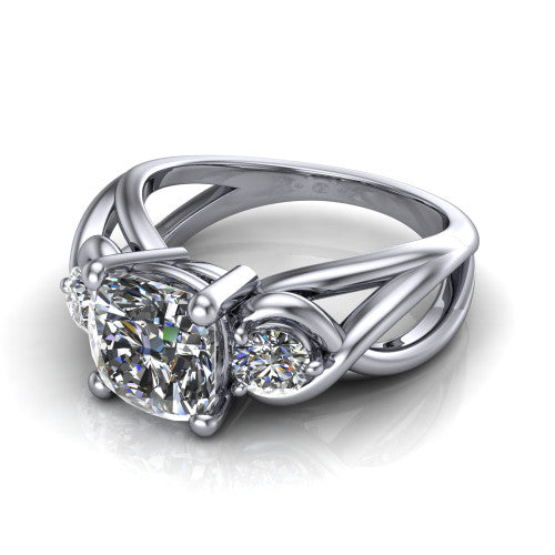 Ottilie cushion three stone engagement ring in Platinum, three-quarter perspective showing the brilliant cushion-cut center diamond flanked by two round side diamonds on a braided ribbon shank