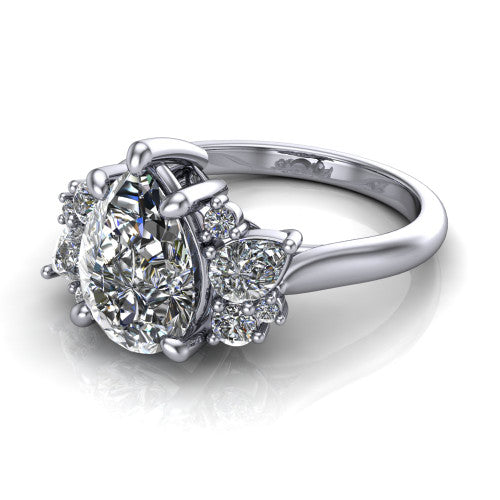 Evie pear three stone engagement ring in Platinum, three-quarter perspective showing the cathedral rise and accent clusters fanning out on both sides of the center
