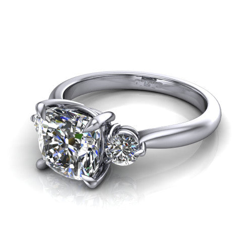 Juniper cushion three stone engagement ring in Platinum, three-quarter perspective showing the brilliant cushion-cut center diamond flanked by two round side diamonds on a rounded plain band