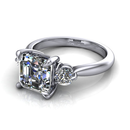 Juniper square emerald three stone engagement ring in Platinum, three-quarter perspective showing the step-cut square emerald center diamond flanked by two round side diamonds on a rounded plain band