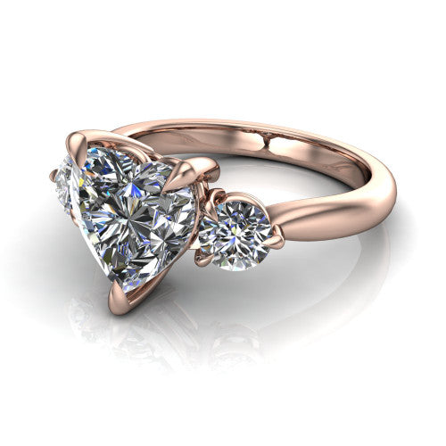 Juniper heart three stone engagement ring in 14K Rose Gold, three-quarter perspective showing the brilliant heart-shaped center diamond flanked by two round side diamonds on a rounded plain band
