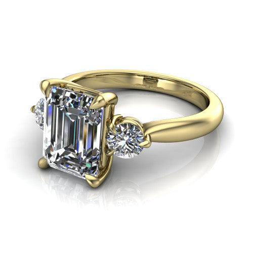 Juniper emerald three stone engagement ring in 14K Yellow Gold, three-quarter perspective showing the step-cut emerald center diamond flanked by two round side diamonds on a rounded plain band