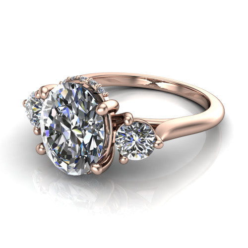 Edith oval hidden halo engagement ring in 14K Rose Gold, three-quarter perspective showing the brilliant oval center diamond flanked by two round side diamonds with a hidden pave halo beneath the center stone