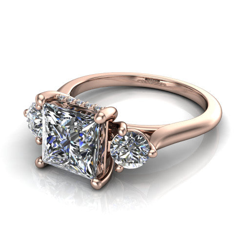 Edith princess hidden halo engagement ring in 18K Rose Gold, three-quarter perspective showing the brilliant princess-cut center diamond flanked by two round side diamonds with a hidden pave halo beneath the center stone