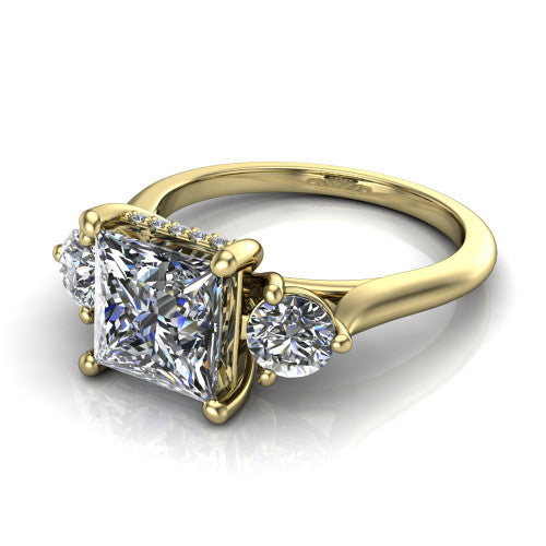 Edith princess hidden halo engagement ring in 18K Yellow Gold, three-quarter perspective showing the brilliant princess-cut center diamond flanked by two round side diamonds with a hidden pave halo beneath the center stone