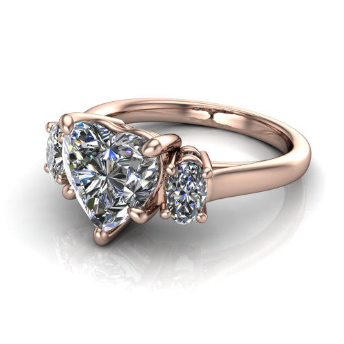 Imogen heart three stone engagement ring in 14K Rose Gold, three-quarter perspective showing the center diamond between two round side stones on a slim polished band