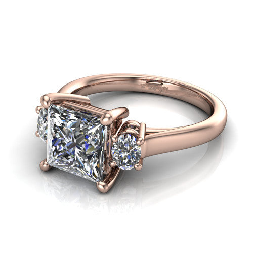 Imogen princess three stone engagement ring in 18K Rose Gold, three-quarter perspective showing the center diamond between two round side stones on a slim polished band