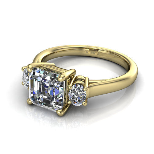 Imogen asscher three stone engagement ring in 14K Yellow Gold, three-quarter perspective showing the center diamond between two round side stones on a slim polished band
