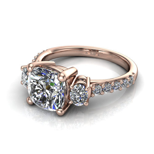Poppy cushion three stone engagement ring in 14K Rose Gold, three-quarter perspective showing the center diamond between two round side stones above a pav&eacute; shank