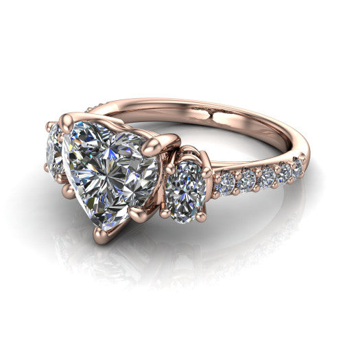 Poppy heart three stone engagement ring in 18K Rose Gold, three-quarter perspective showing the center diamond between two round side stones above a pav&eacute; shank