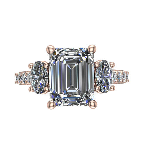 Poppy emerald three stone engagement ring in 18K Rose Gold, top-down view showing the center diamond flanked by two round side stones in a classic three stone setting