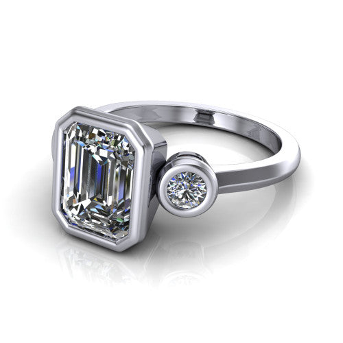 Daisy emerald three stone engagement ring in 14K White Gold, three-quarter perspective showing the bezel-set center between two bezel-set round side stones on a slim polished band