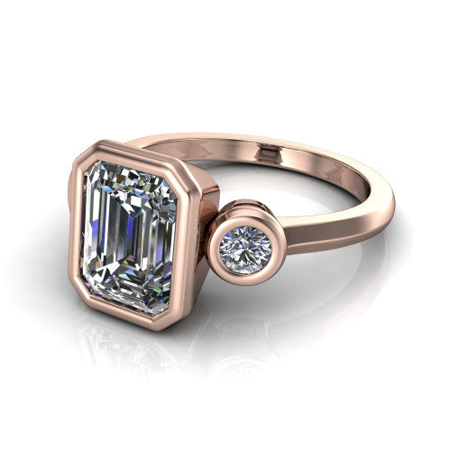 Daisy emerald three stone engagement ring in 18K Rose Gold, three-quarter perspective showing the bezel-set center between two bezel-set round side stones on a slim polished band