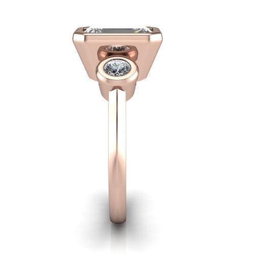 Daisy emerald three stone engagement ring in 18K Rose Gold, side profile showing the bezel-set round side stone and the smooth polished band