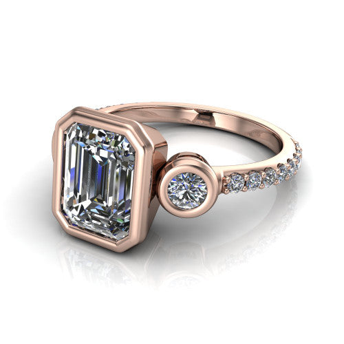 Chloe emerald three stone engagement ring in 14K Rose Gold, three-quarter perspective showing the bezel-set center between two bezel-set round side stones above a pav&eacute; shank