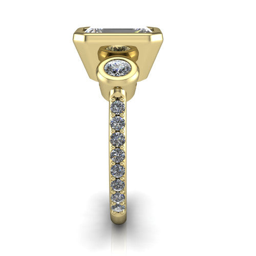 Chloe emerald three stone engagement ring in 18K Yellow Gold, side profile showing the round bezel side stone and the pav&eacute; diamonds running down the shank