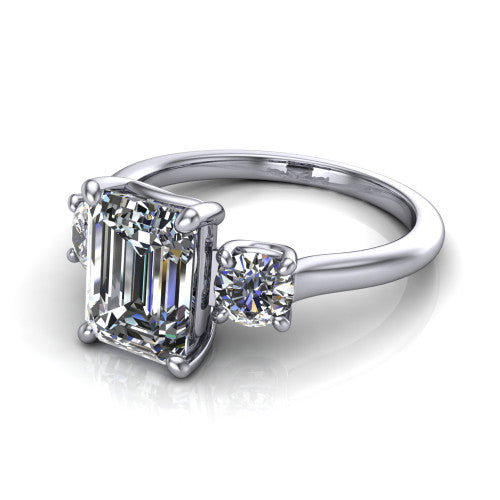 Emma emerald three stone engagement ring in Platinum, three-quarter perspective showing the center diamond between two round side stones on a slim polished band
