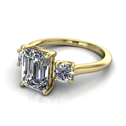Emma emerald three stone engagement ring in 18K Yellow Gold, three-quarter perspective showing the center diamond between two round side stones on a slim polished band