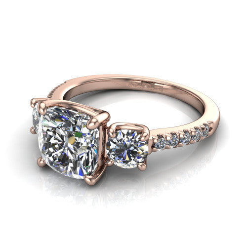 Celeste cushion three stone engagement ring in 18K Rose Gold, three-quarter perspective showing the center diamond between two round side stones above a pav&eacute; shank