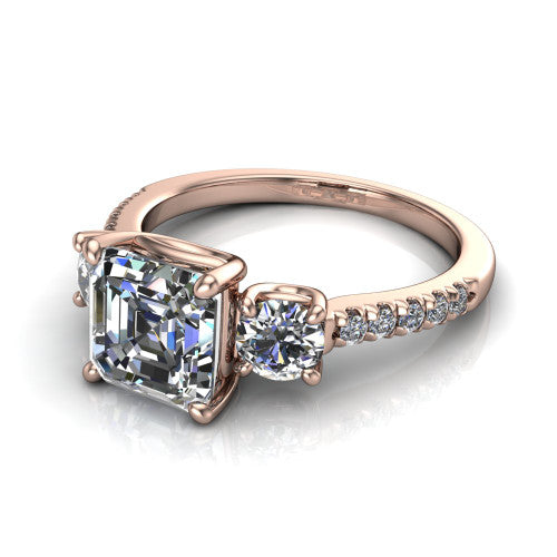 Celeste asscher three stone engagement ring in 18K Rose Gold, three-quarter perspective showing the center diamond between two round side stones above a pav&eacute; shank