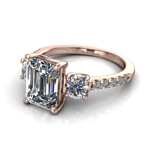 Celeste emerald three stone engagement ring in 14K Rose Gold, three-quarter perspective showing the center diamond between two round side stones above a pav&eacute; shank
