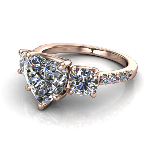 Celeste heart three stone engagement ring in 18K Rose Gold, three-quarter perspective showing the center diamond between two round side stones above a pav&eacute; shank