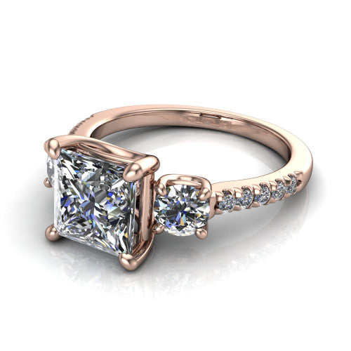 Celeste princess three stone engagement ring in 14K Rose Gold, three-quarter perspective showing the center diamond between two round side stones above a pav&eacute; shank
