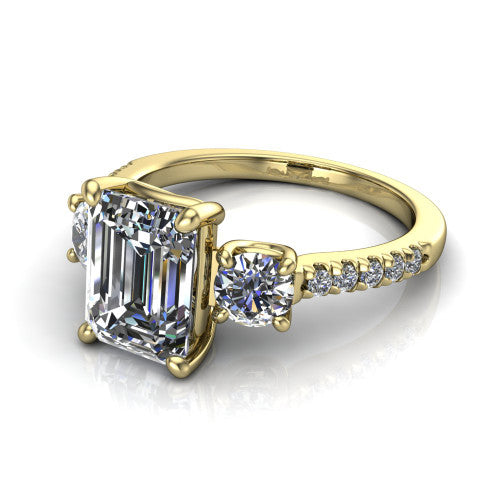 Celeste emerald three stone engagement ring in 18K Yellow Gold, three-quarter perspective showing the center diamond between two round side stones above a pav&eacute; shank