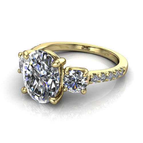 Celeste oval three stone engagement ring in 18K Yellow Gold, three-quarter perspective showing the center diamond between two round side stones above a pav&eacute; shank
