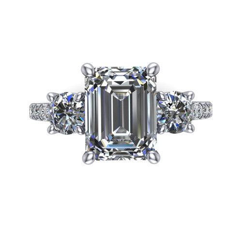 Celeste emerald three stone engagement ring in Platinum, top-down view showing the center diamond flanked by two round side stones in a classic three stone setting