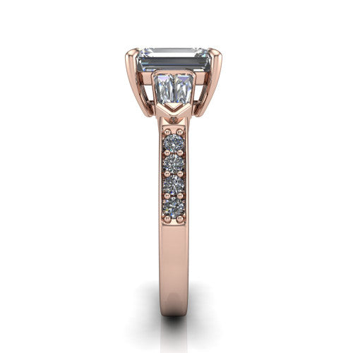 Audrey emerald three stone engagement ring in 18K Rose Gold, side profile showing the tapered baguette side stone and the round diamonds running down the shank