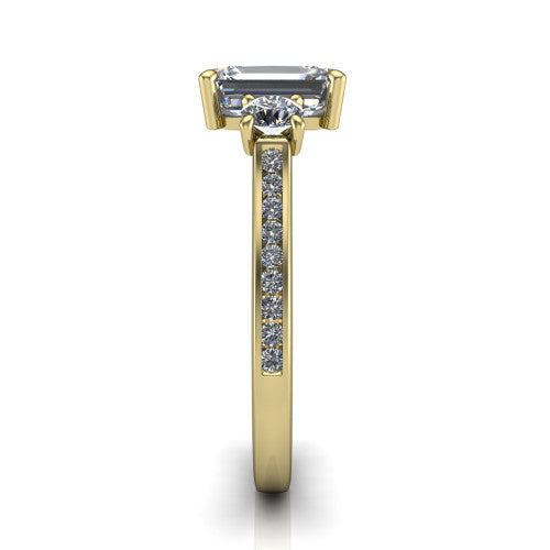 Saoirse emerald three stone engagement ring in 18K Yellow Gold, side profile showing the round side stone and the pav&eacute; diamonds running down the shank