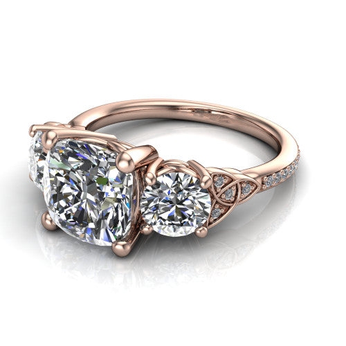 Zion cushion three stone engagement ring in 14K Rose Gold, three-quarter perspective showing the center diamond between two round side stones with Celtic trinity-knot shoulders above a pav&eacute; shank