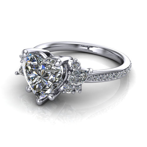 Mila heart three stone engagement ring in Platinum, three-quarter perspective showing the center diamond flanked by round accent clusters above a pav&eacute; shank