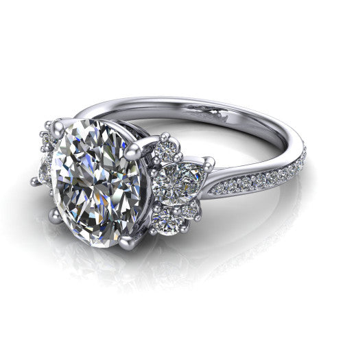 Mila oval three stone engagement ring in Platinum, three-quarter perspective showing the center diamond flanked by round accent clusters above a pav&eacute; shank