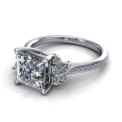 Mila princess three stone engagement ring in Platinum, three-quarter perspective showing the center diamond flanked by round accent clusters above a pav&eacute; shank