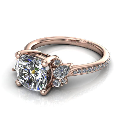 Mila cushion three stone engagement ring in 18K Rose Gold, three-quarter perspective showing the center diamond flanked by round accent clusters above a pav&eacute; shank