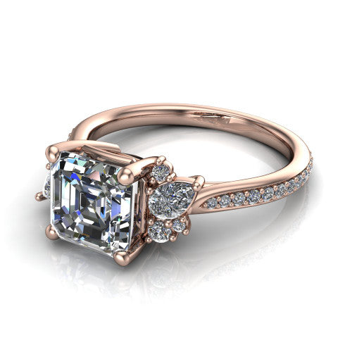 Mila asscher three stone engagement ring in 18K Rose Gold, three-quarter perspective showing the center diamond flanked by round accent clusters above a pav&eacute; shank
