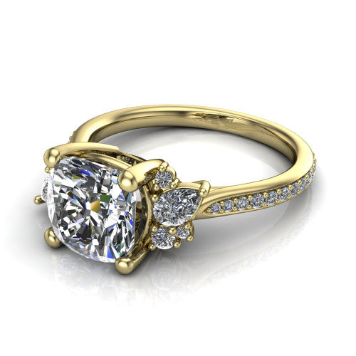 Mila cushion three stone engagement ring in 14K Yellow Gold, three-quarter perspective showing the center diamond flanked by round accent clusters above a pav&eacute; shank
