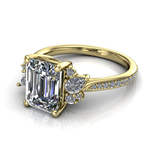 Mila emerald three stone engagement ring in 14K Yellow Gold, three-quarter perspective showing the center diamond flanked by round accent clusters above a pav&eacute; shank