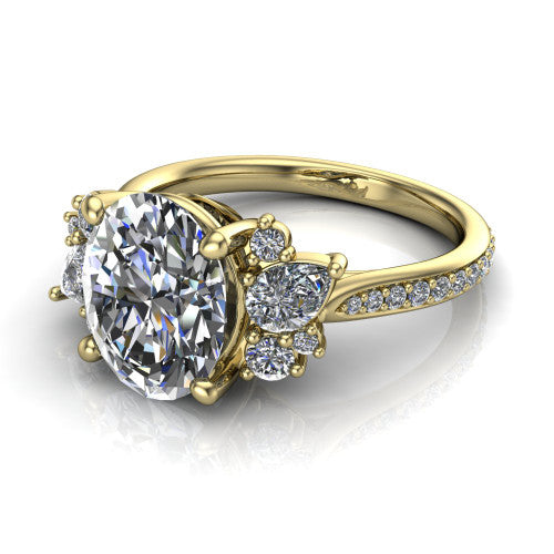 Mila oval three stone engagement ring in 18K Yellow Gold, three-quarter perspective showing the center diamond flanked by round accent clusters above a pav&eacute; shank