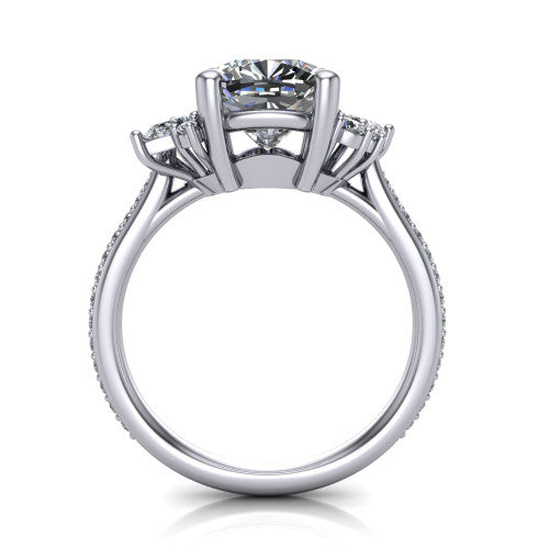 Mila cushion three stone engagement ring in Platinum, through-finger front profile showing the center head raised above the round accent clusters and pav&eacute; band
